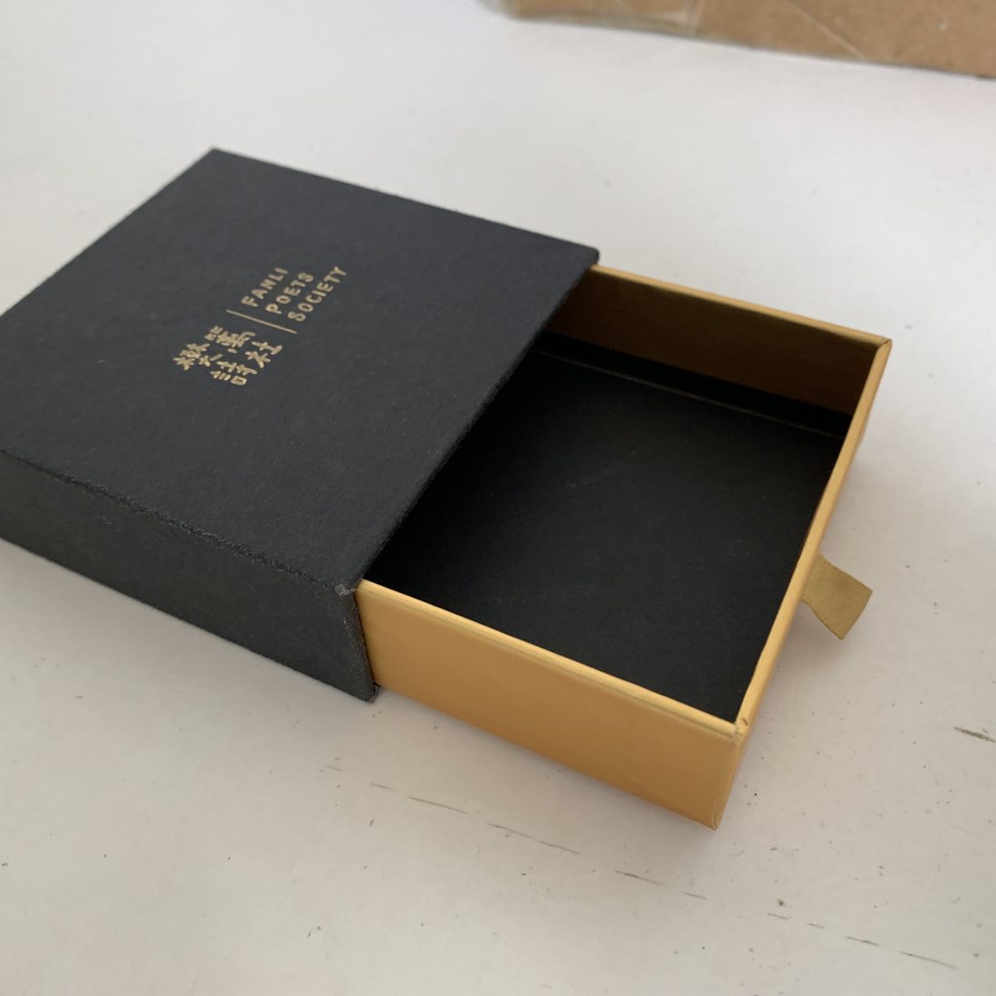 Black sliding drawer box with gold foil and a fitted interior tray, pulled open